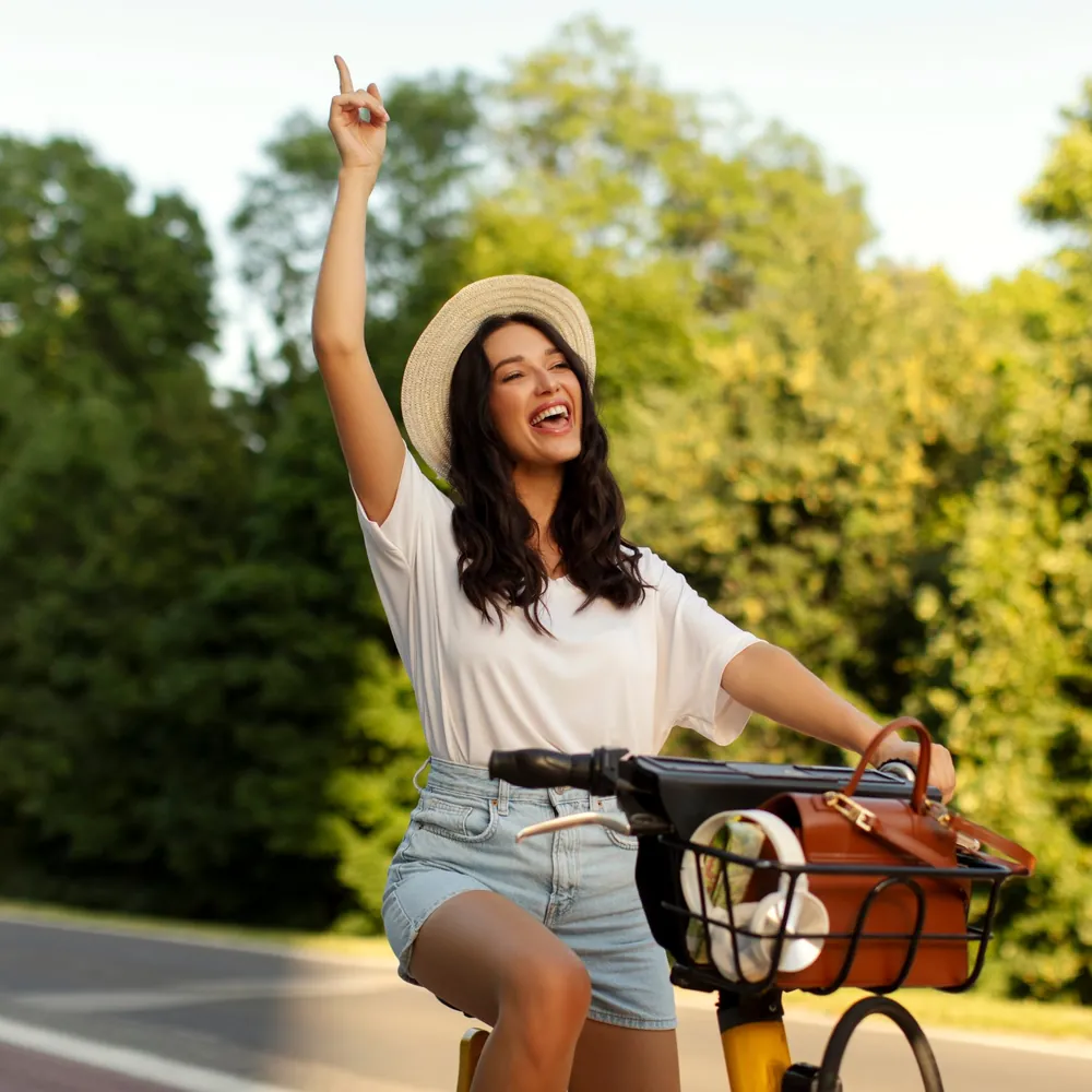 Femme rieuse à vélo, bras levé, exprimant sa voix librement – chakra de la gorge au quotidien